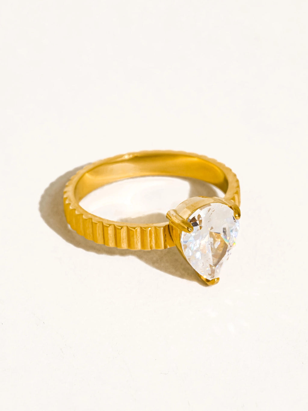 Gold ring with a clear teardrop-shaped cz stone on a white background