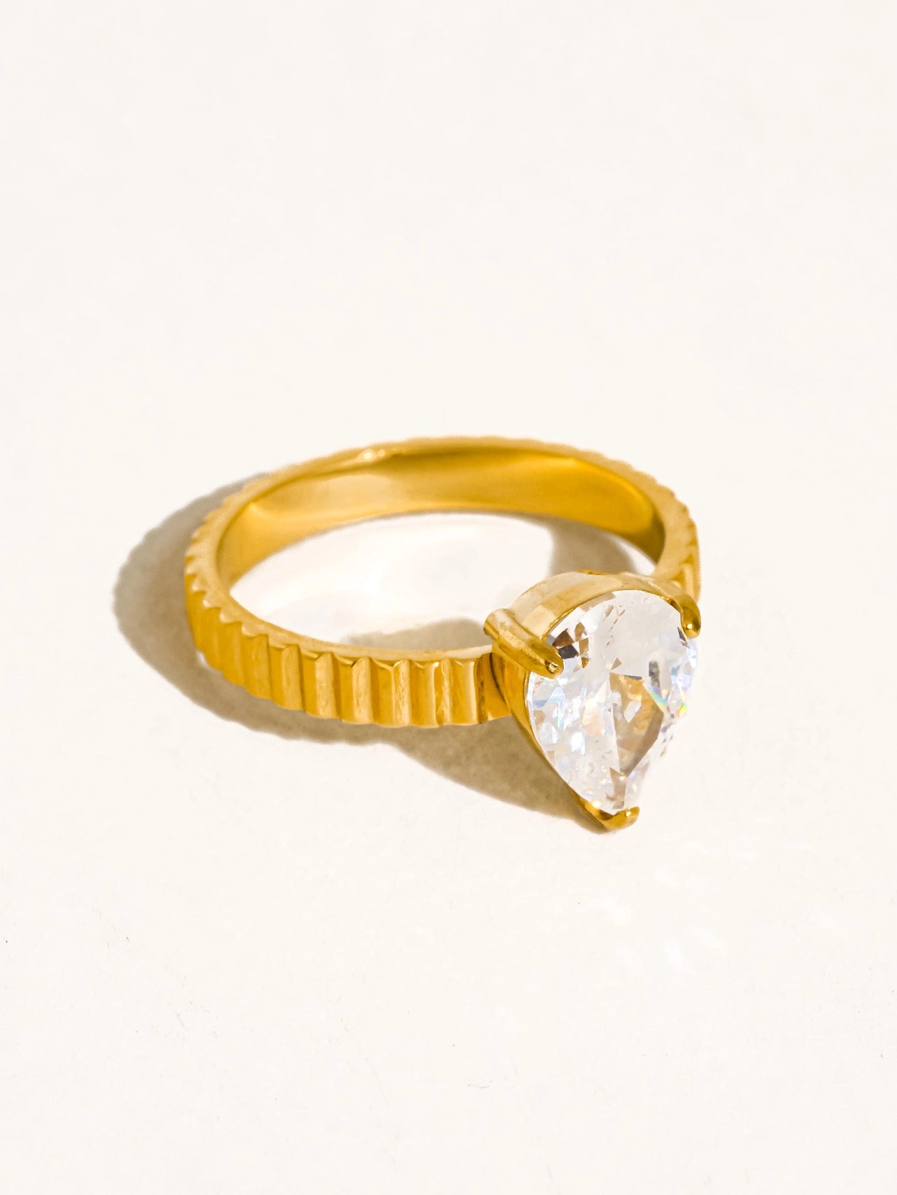 Gold ring with a clear teardrop-shaped cz stone on a white background