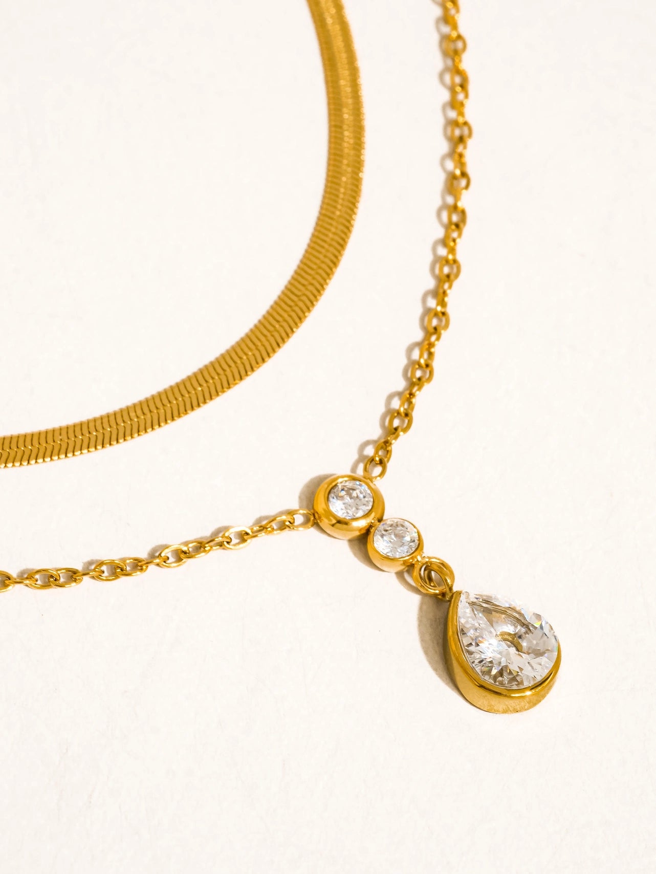 Gold necklace with teardrop-shaped cz pendants on a white background
