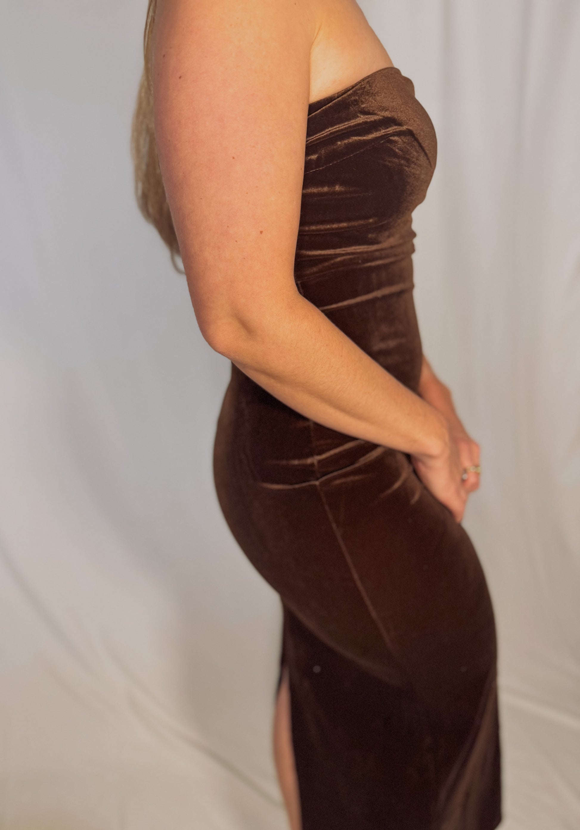 Brown velvet dress with a slit on a plain background
