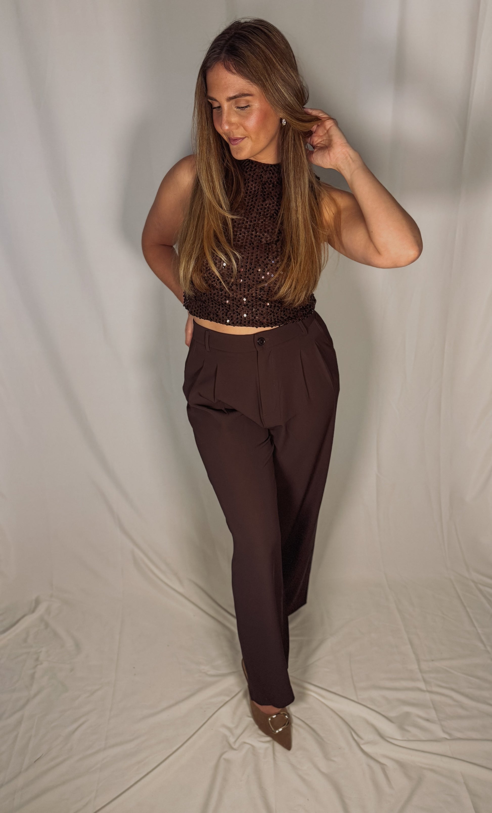 Woman wearing a brown beaded top and matching pants against a plain background