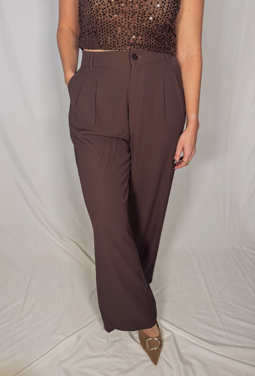 Brown high-waisted pants worn by a person on a plain background