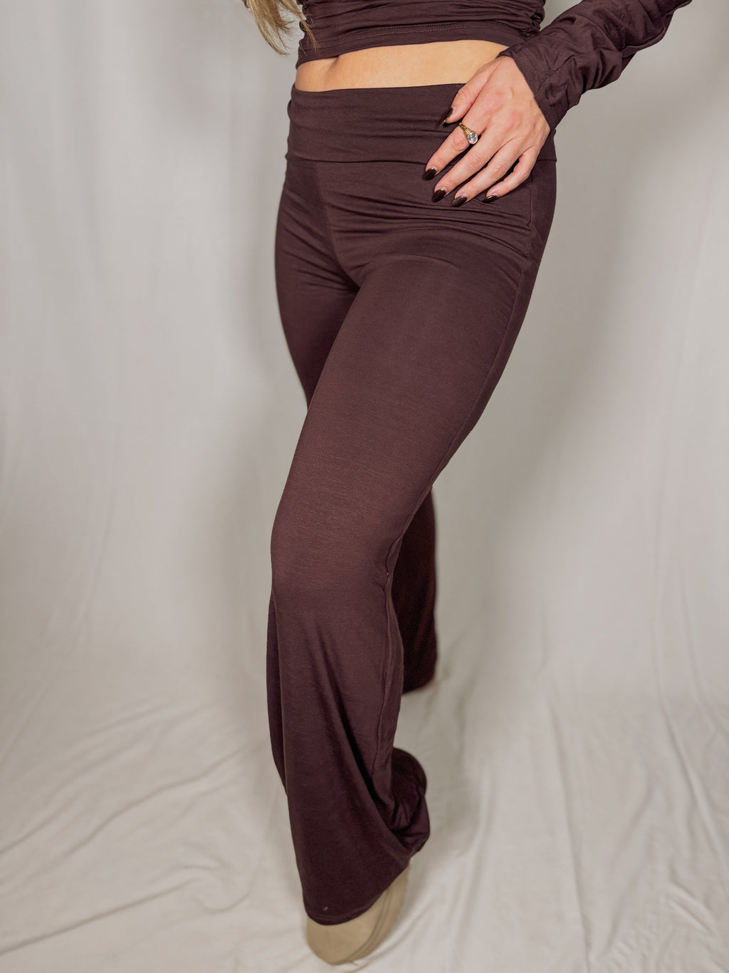 Person wearing brown pants and a matching top on a plain background