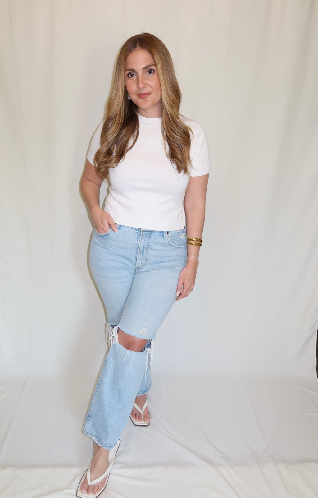 Woman wearing a white top with blue jeans.