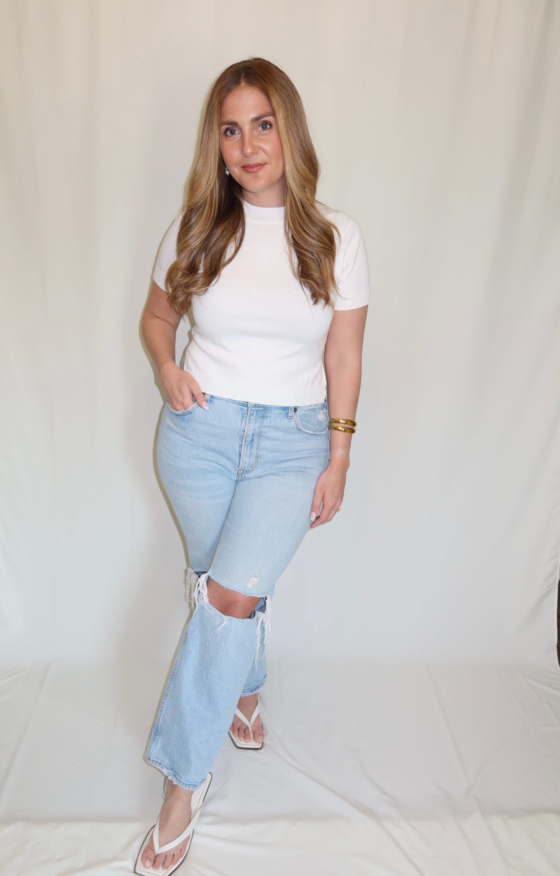 Woman wearing a white top with blue jeans.