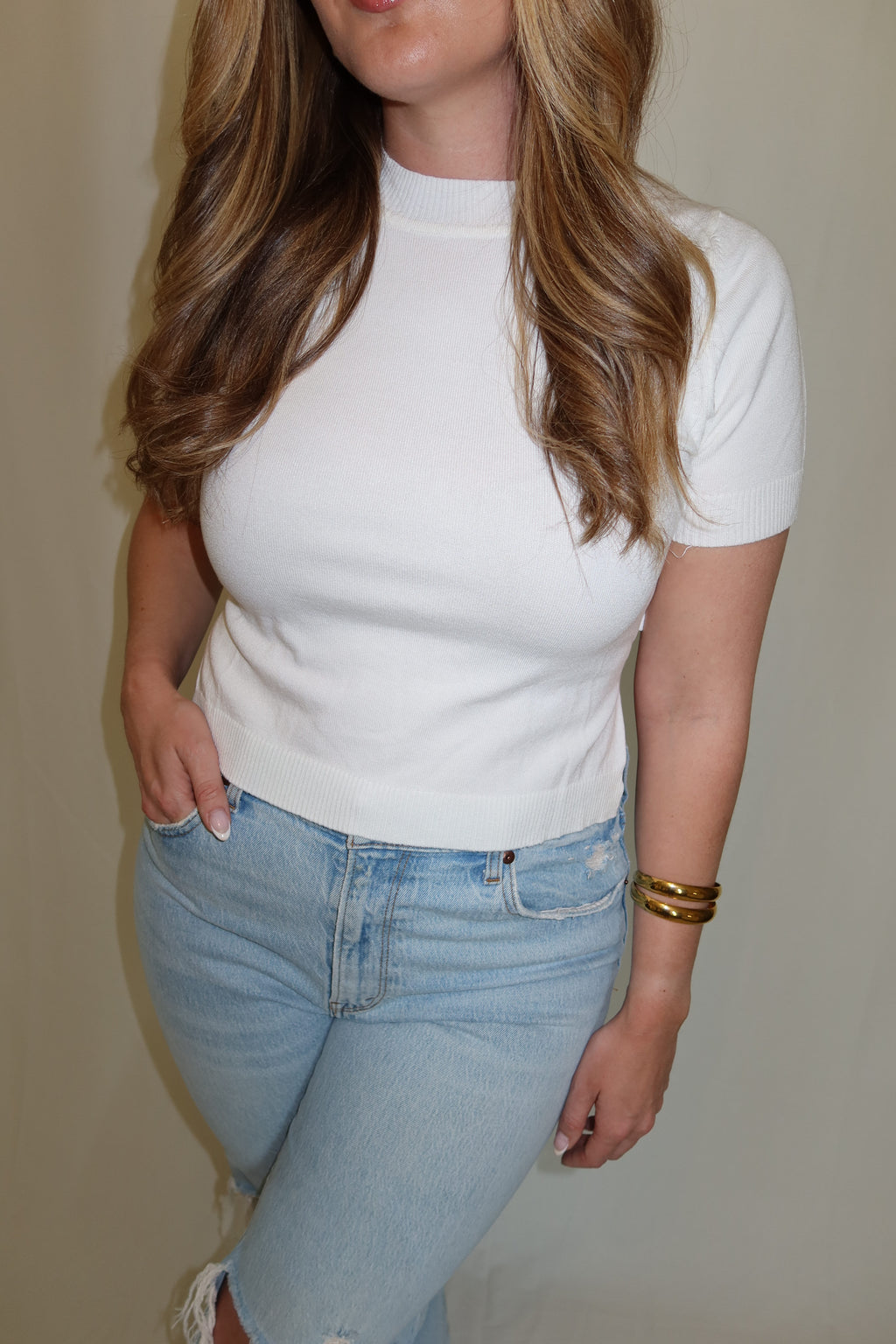Woman wearing a white top with blue jeans.