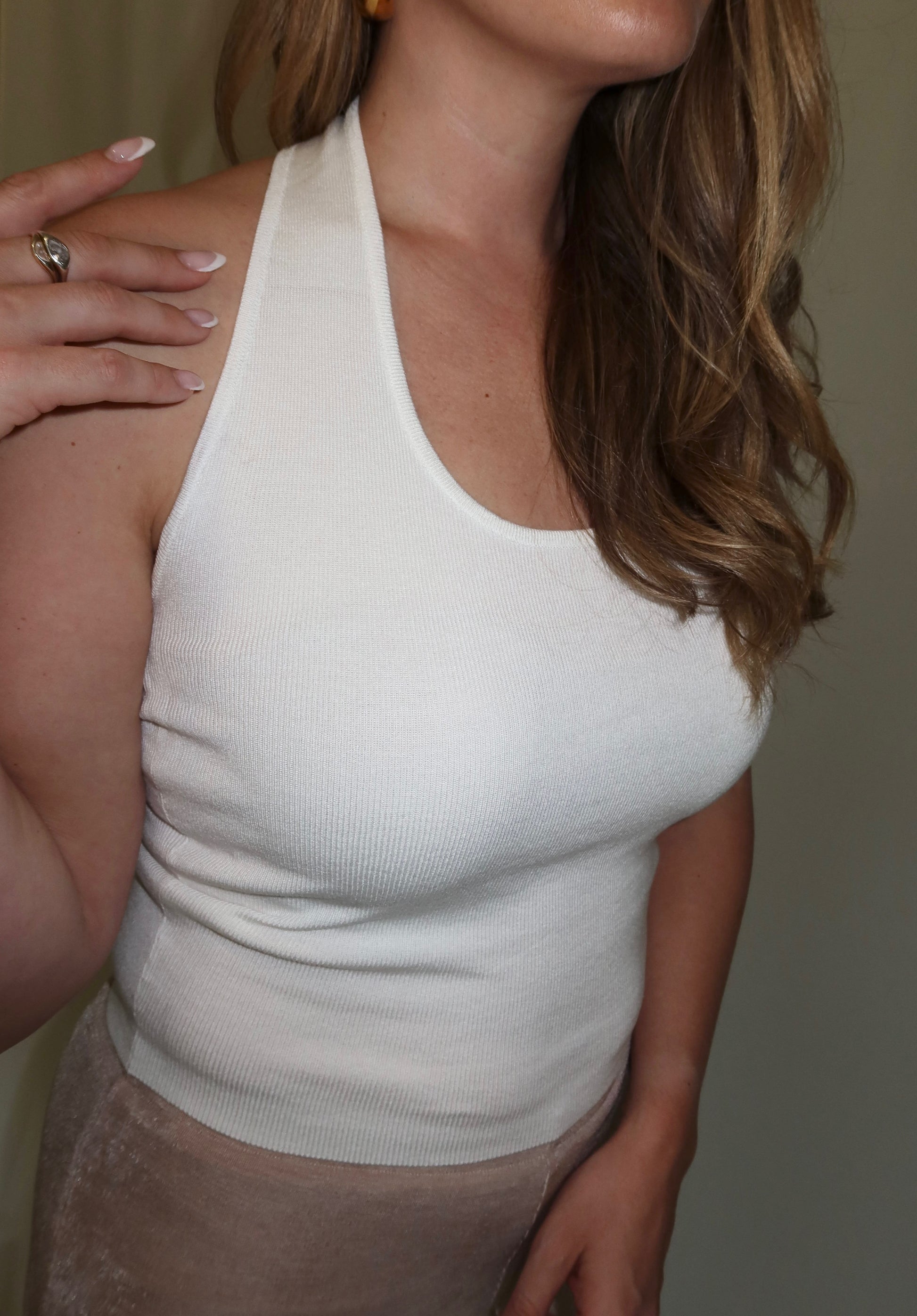 Woman wearing a white halter top with a neutral background