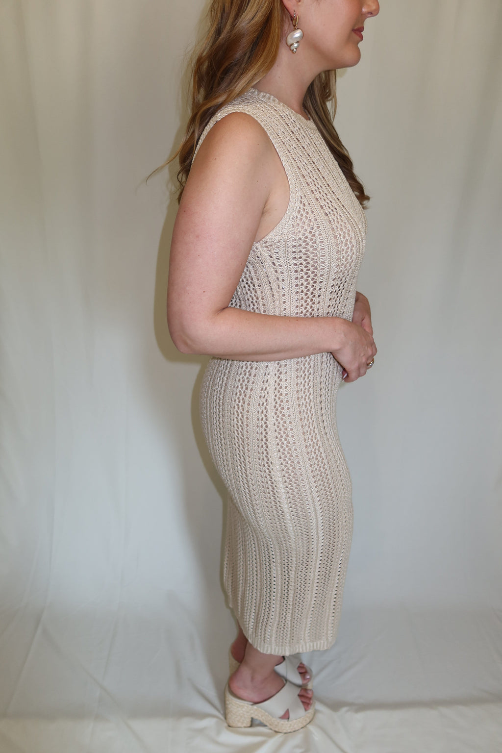 Woman in beige crochet dress on a plain background