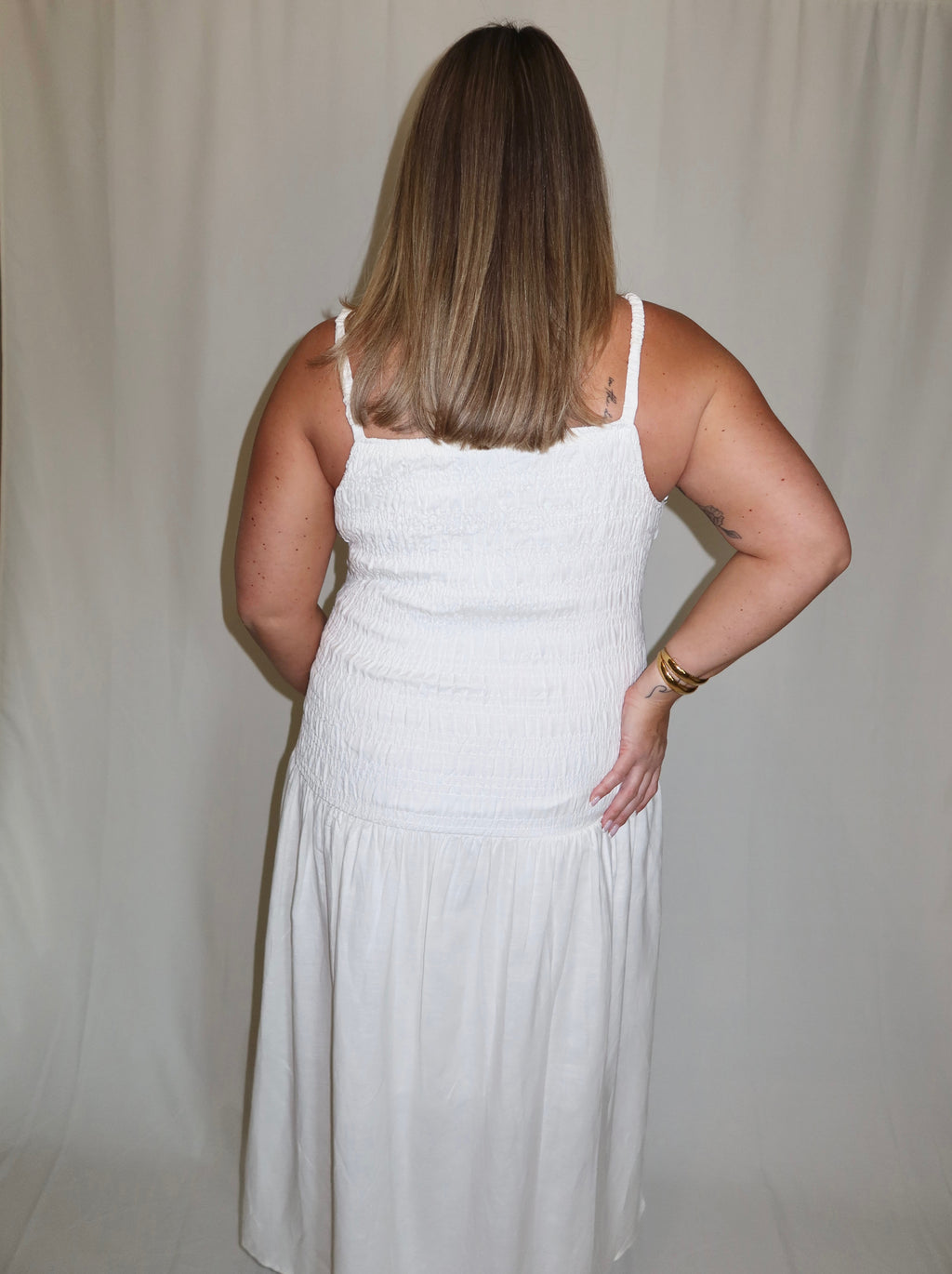 Woman wearing a white dress against a plain background