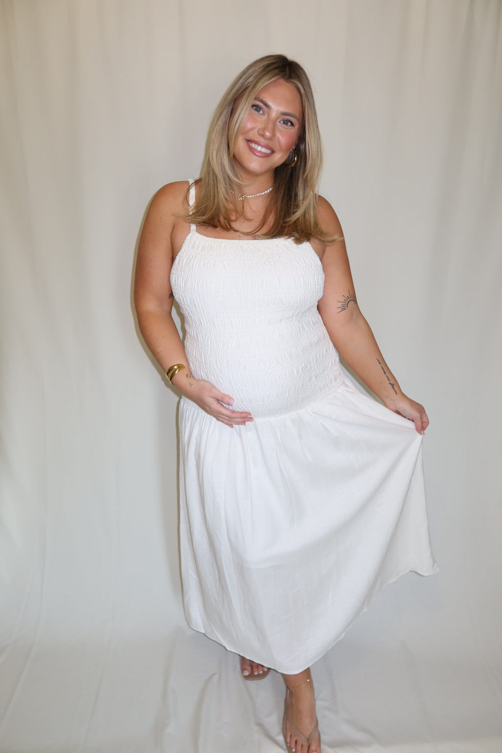 Woman in a white dress standing against a plain background