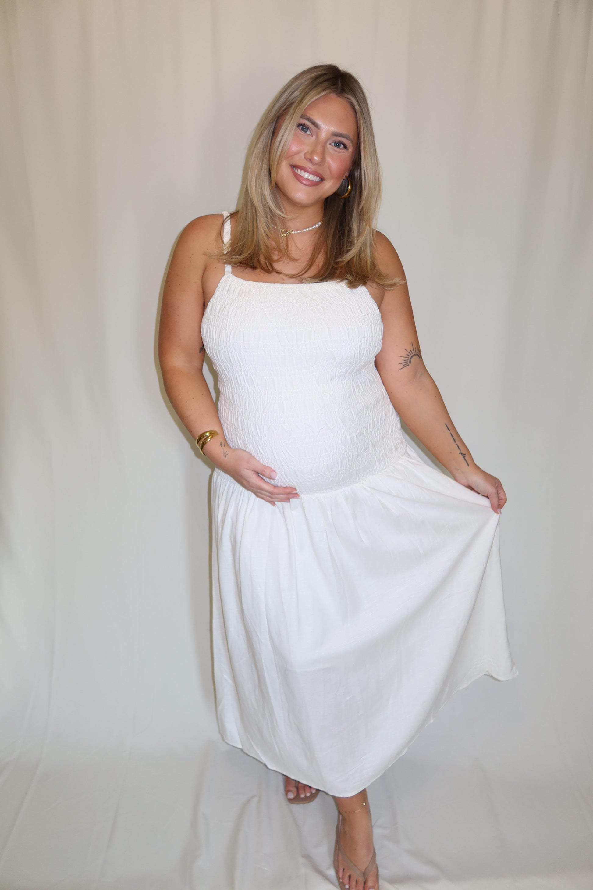 Woman in a white dress standing against a plain background