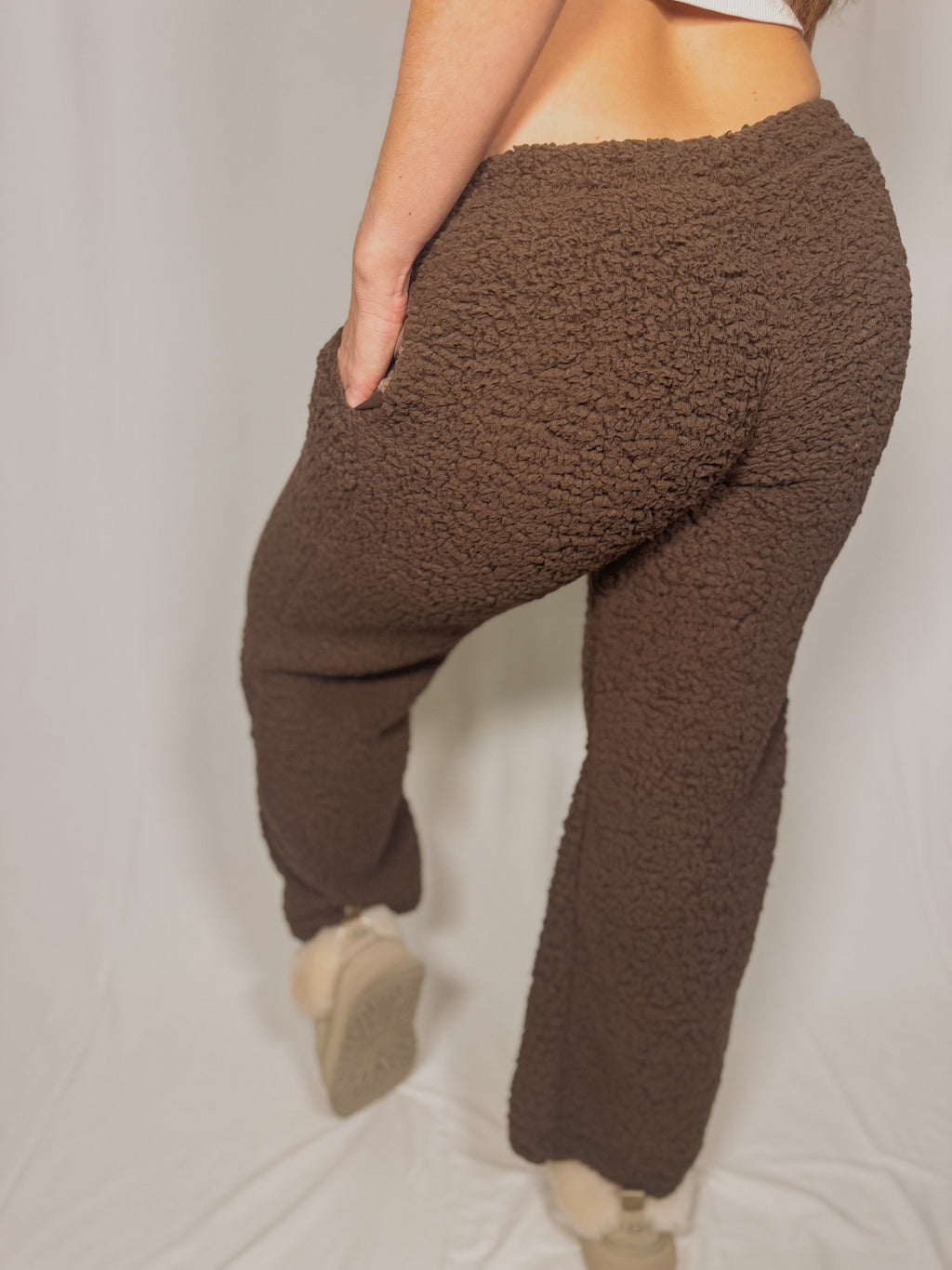 Brown teddy fleece pants worn by a person on a plain background