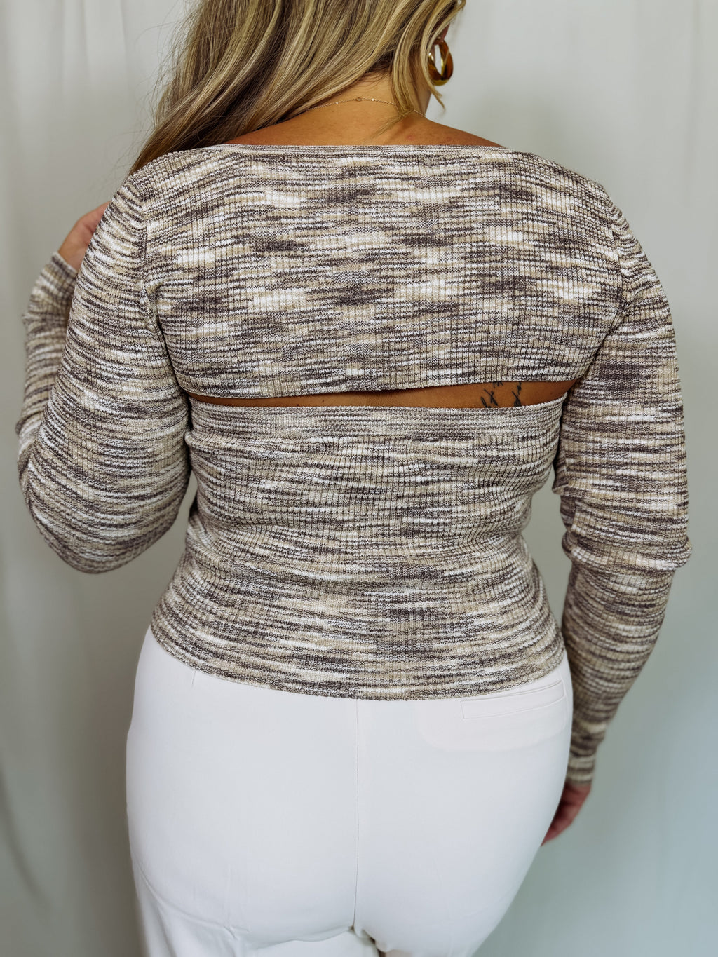 Girl wearing a patterned bolero shrug over a tube top shown from the back