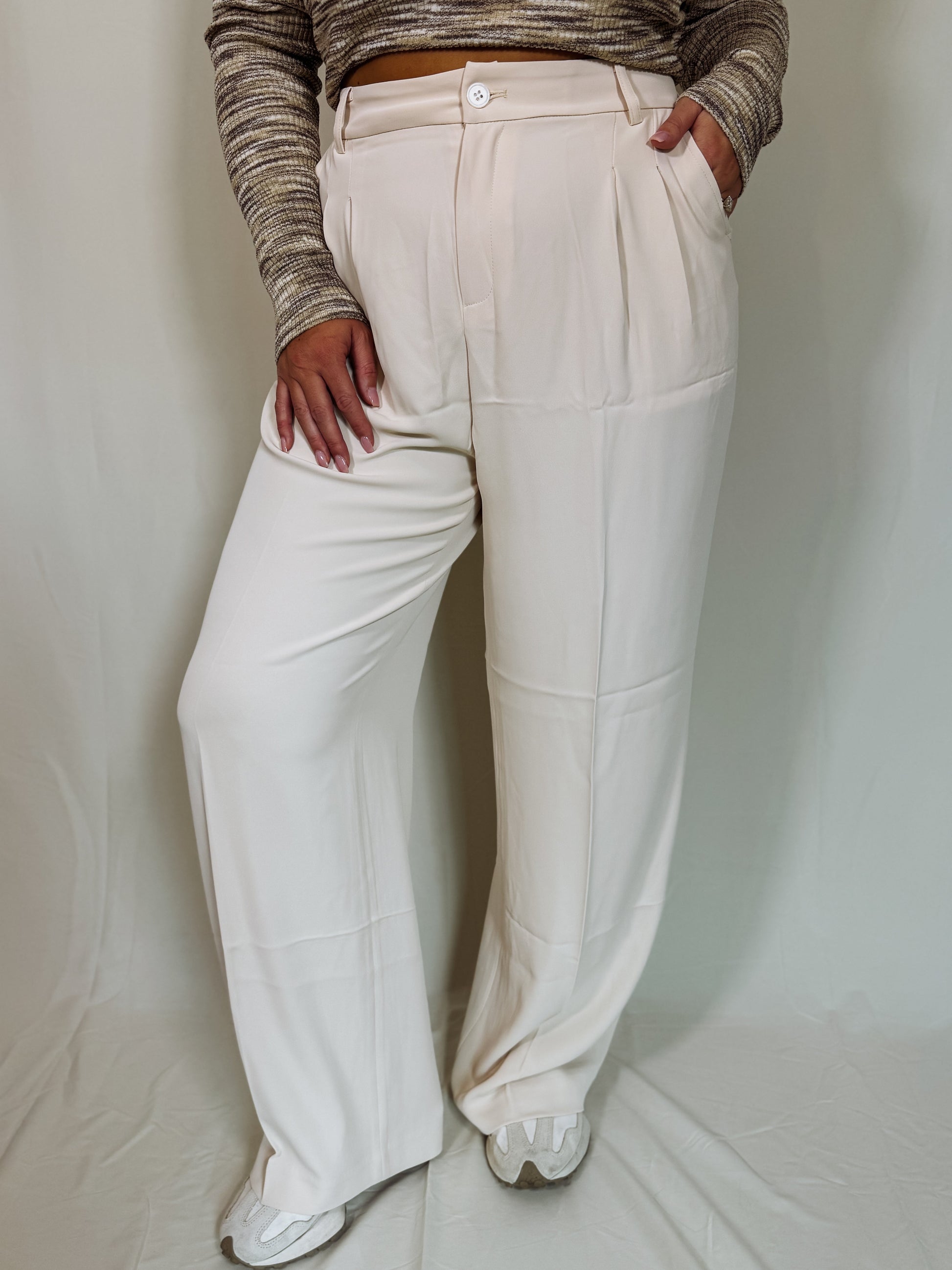 Person wearing beige wide-leg pants and a patterned top on a plain background