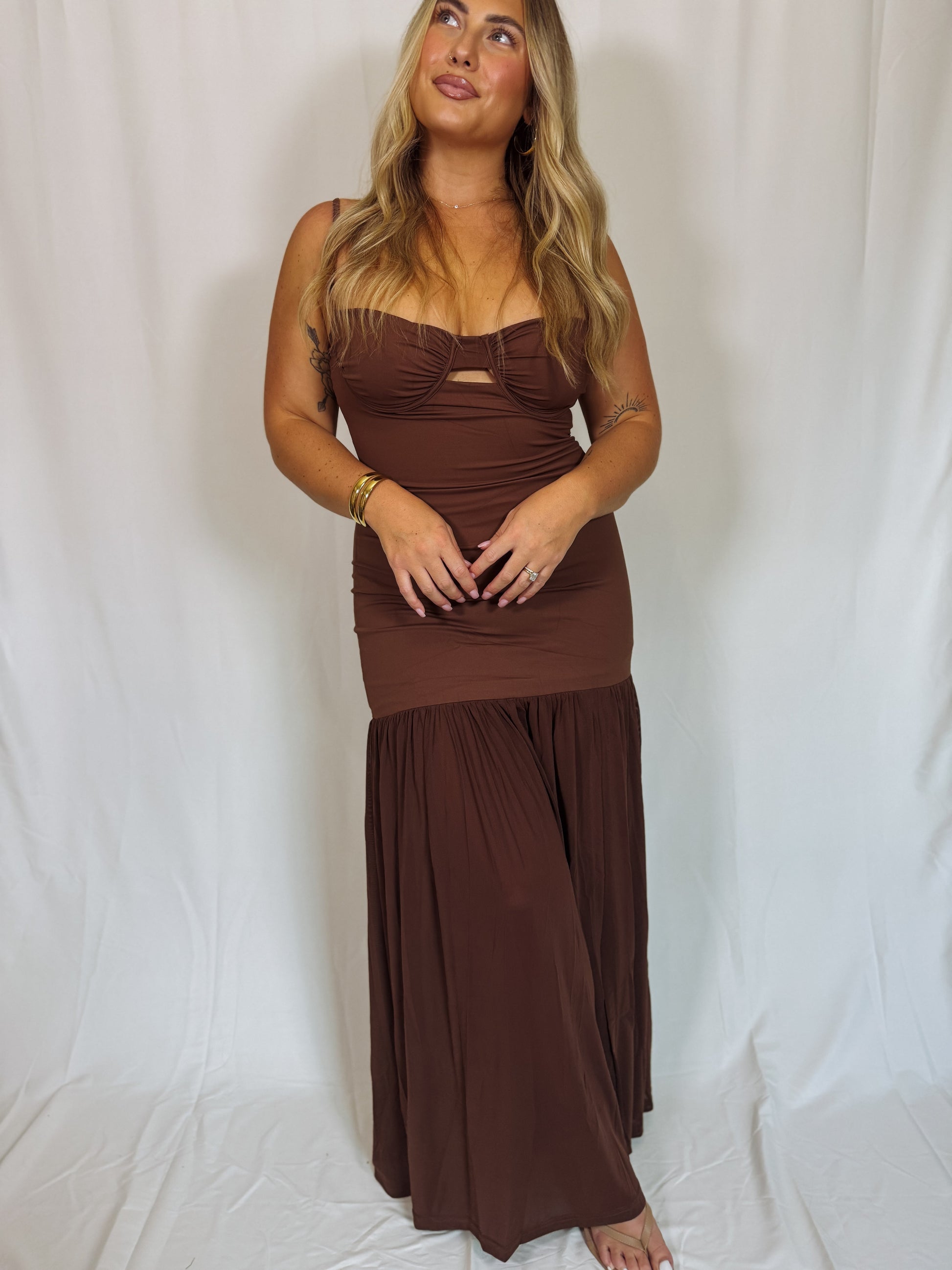 Woman wearing a brown trumpet dress against a white background