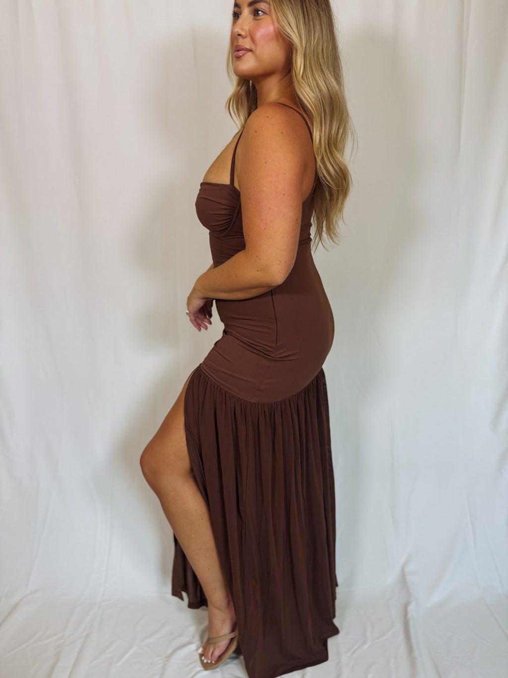 Woman wearing a brown dress with a slit on a white background