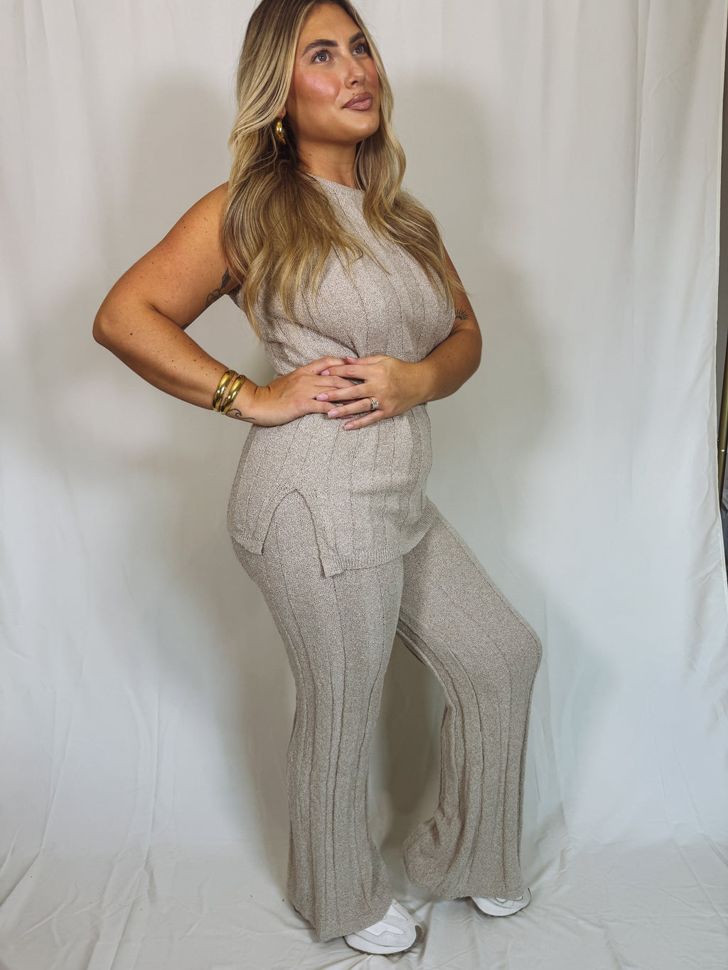 Woman wearing a beige ribbed knit outfit against a white background