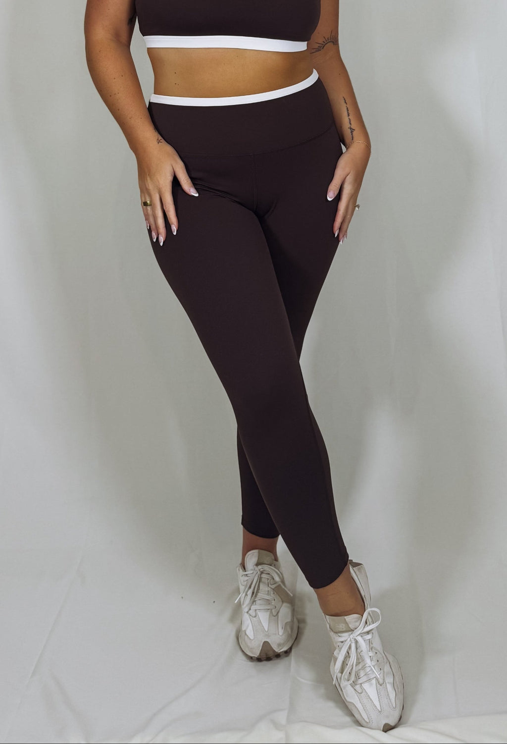 Woman wearing a black sports bra and leggings set on a white background