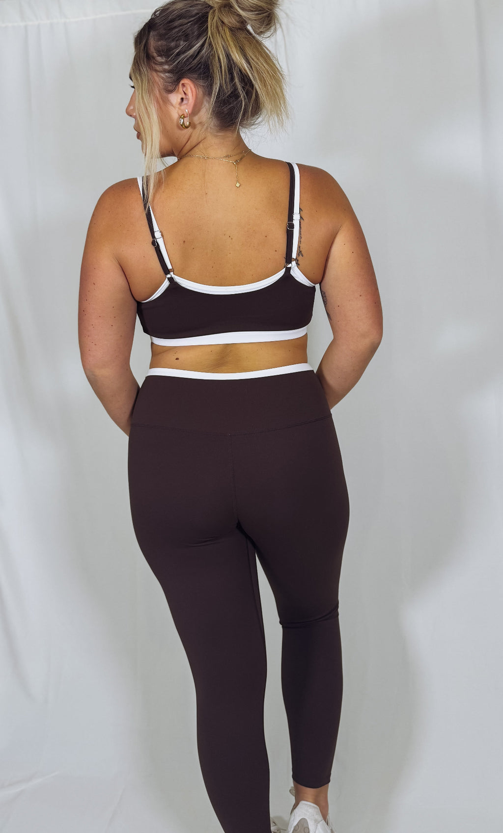 Person wearing a black sports bra and leggings set on a plain background