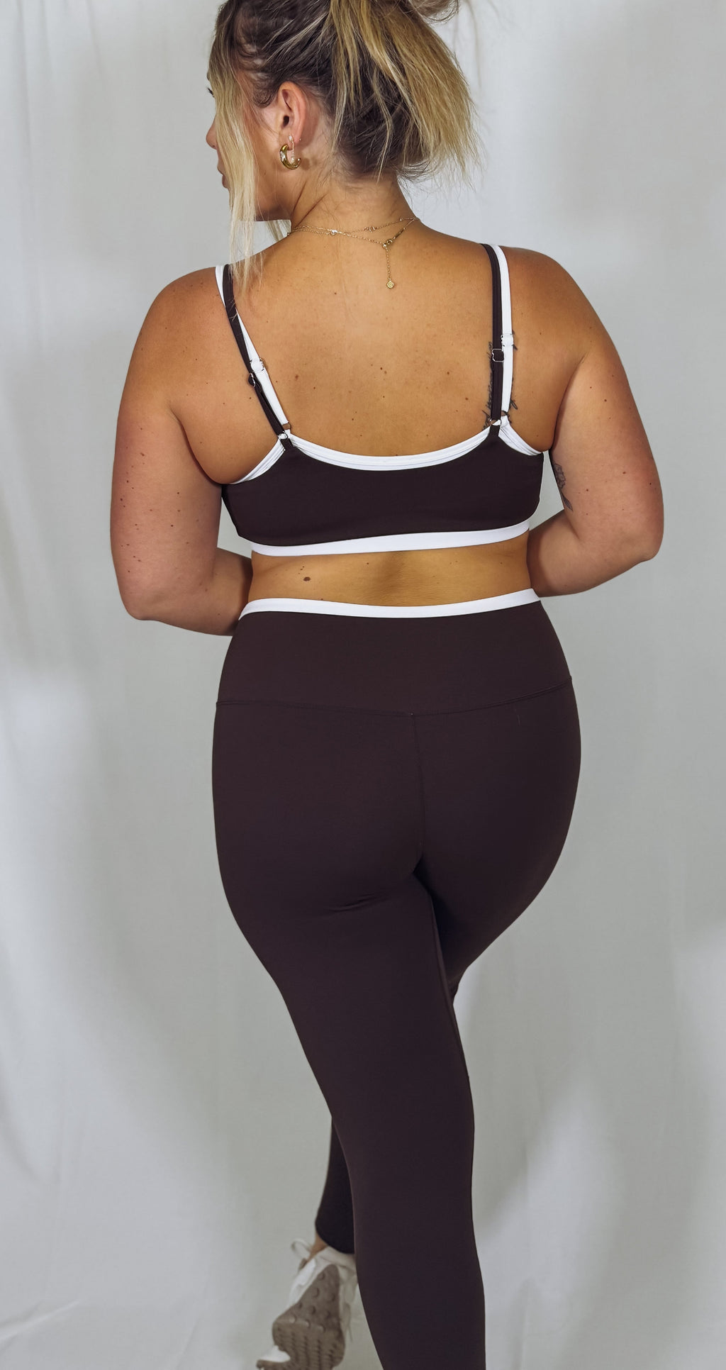 Person wearing a brown sports bra and leggings on a plain background