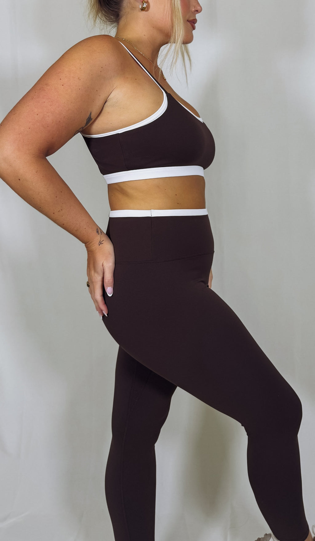 Person wearing a brown sports bra and leggings set on a plain background