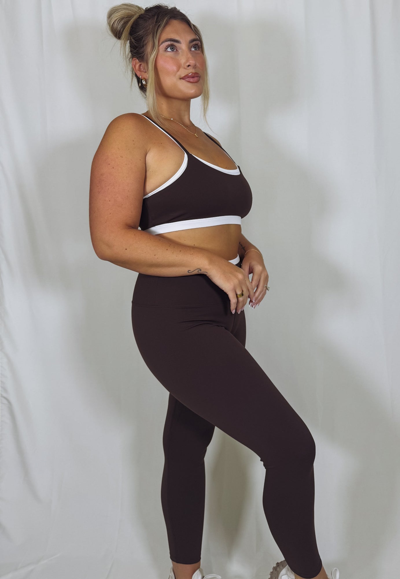 Woman wearing a brown sports bra and leggings set against a plain background