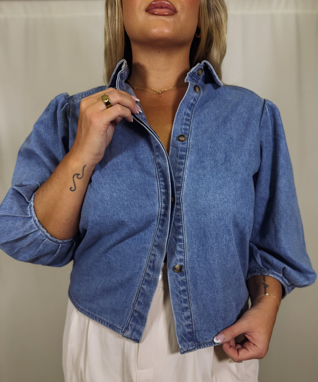 Person wearing a blue denim shirt against a neutral background