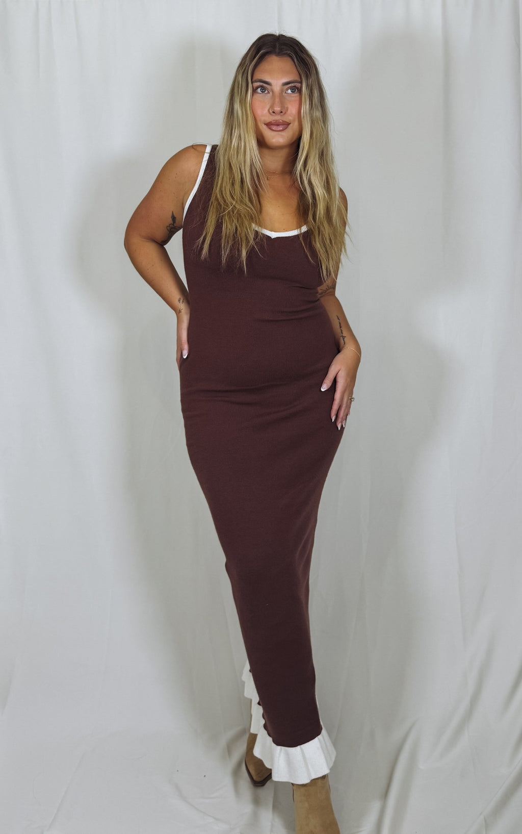 Woman wearing a brown dress with white trim against a plain background